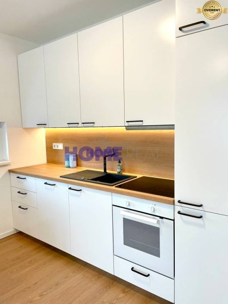 A kitchen unit with light cabinets and a wooden decor floor in a 3-room apartment.