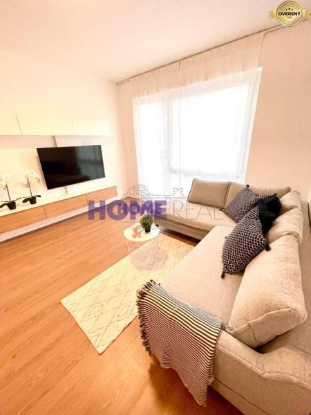 Living room of a three-room apartment with a comfortable sofa and TV, floor with wooden decor.