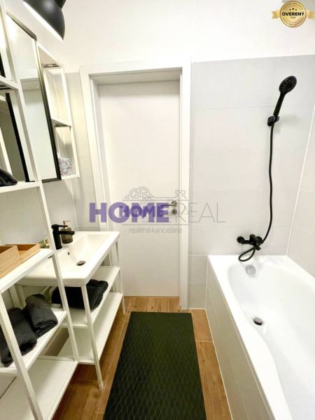 A bathroom in a 3-room apartment with a bathtub, a white sink, and a floor with a wooden decor.