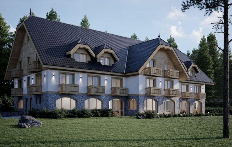 A hotel in the High Tatras with wooden balconies and a stone facade surrounded by greenery.