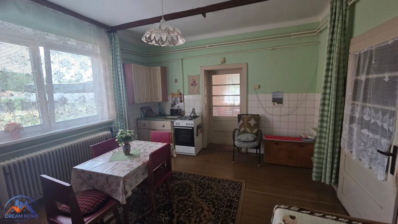 A kitchen in a family house with a dining table, floral curtains, and a stove.