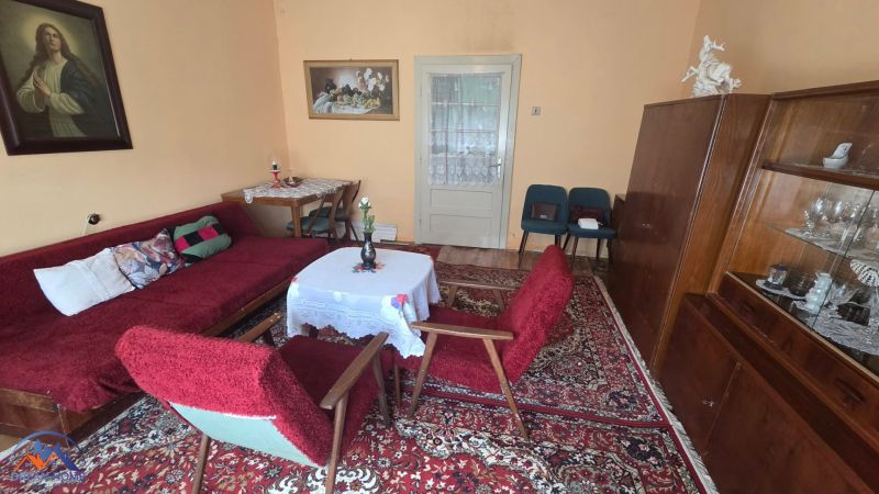 Living room in a family house with a carpet, wooden furniture, and paintings on the walls.