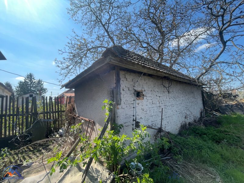 A family house in Bátorove Kosihy, an older building with peeling plaster, surrounded by greenery.