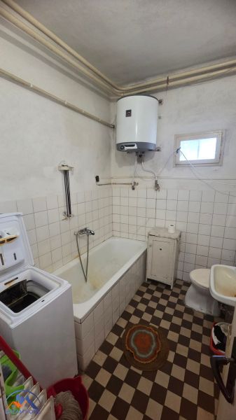 A bathroom in a family house with a bathtub, washing machine, and gas boiler.