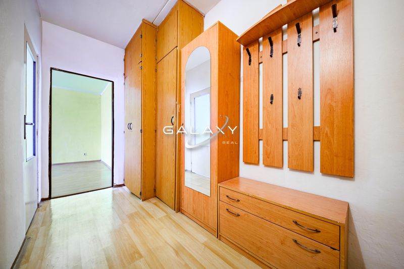 The entrance hall of a 2-room apartment with a wooden decor floor and built-in wardrobes.