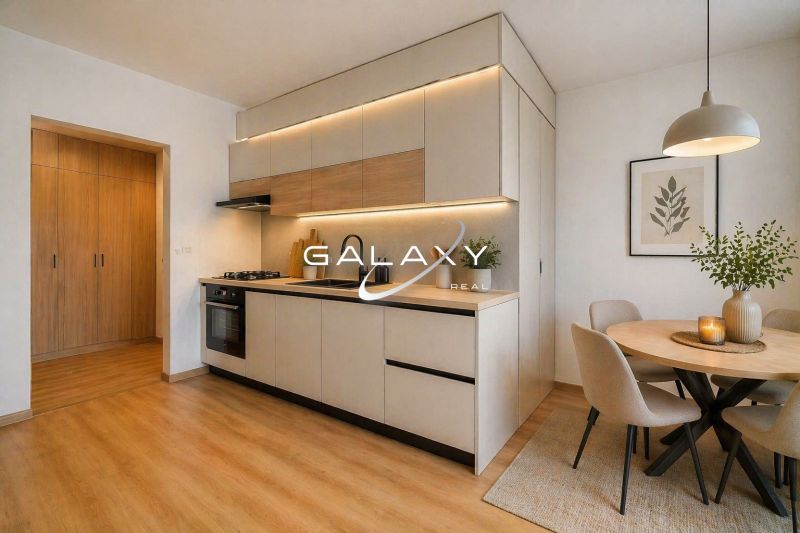 A kitchen in a 2-room apartment with a wooden decor floor, a dining table, and lights.