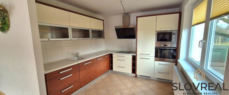 A kitchen with a corner unit in a family house, white cabinets, and ceramic flooring.