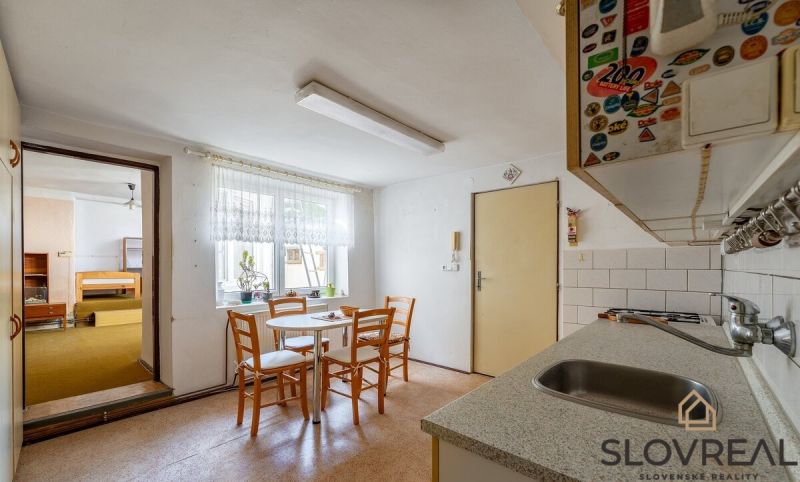 A kitchen in a family house with a dining table and an entrance to the living room.