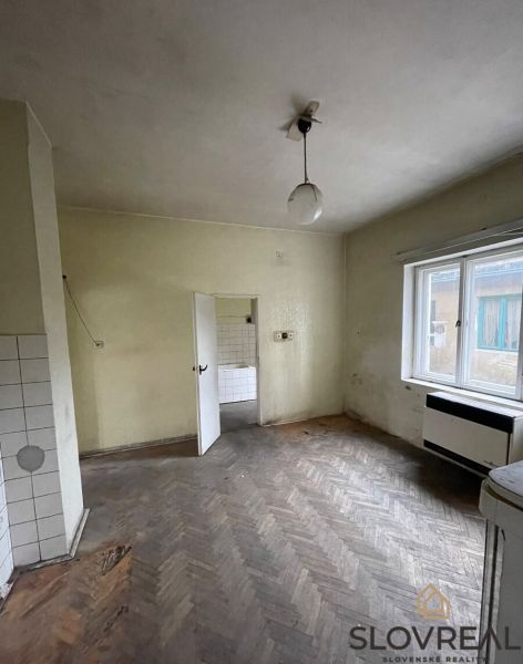 A room with a wooden decor floor and an older radiator in a family house.