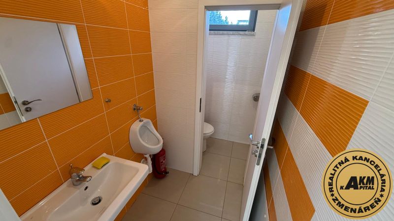 A restroom with orange tiles and ceramic accessories in commercial premises.