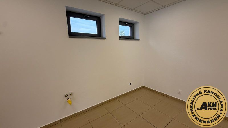 An empty room with two small windows and tiles, commercial space.