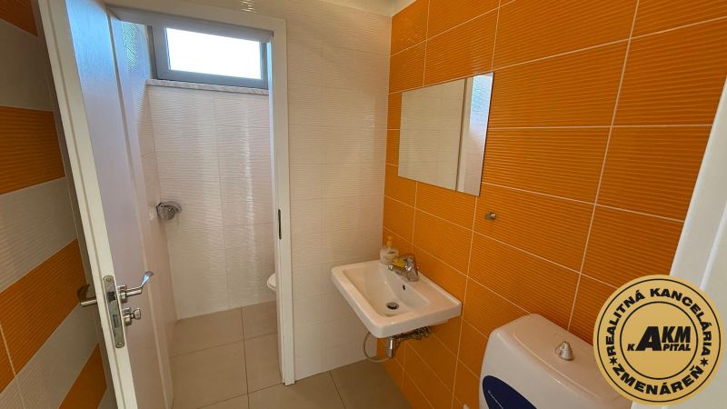 A restroom in commercial premises with orange tiles and a washbasin.