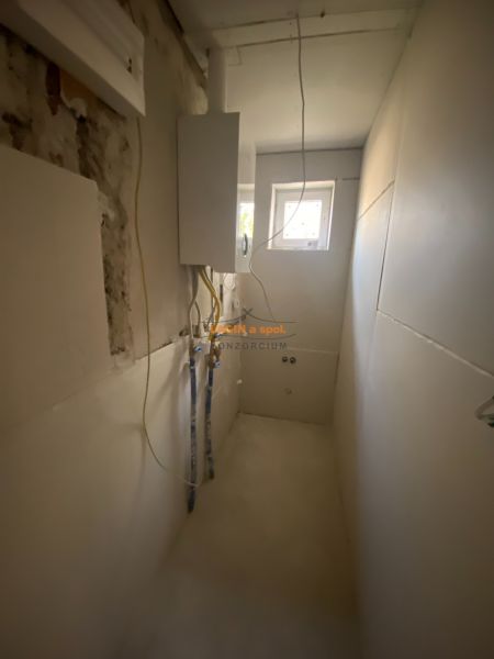 A narrow technical room in a family house with wiring and a small window.