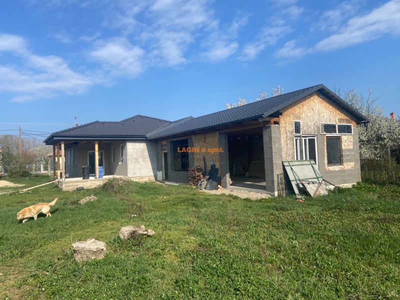 A family house in Encs with a black roof, under construction, surrounded by a grassy plot.
