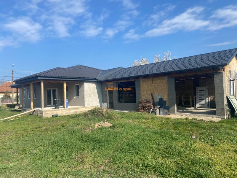A family house in Encs, unplastered with a dark roof and green lawn.