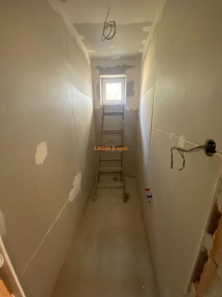 A narrow room in a family house with a ladder and raw walls.