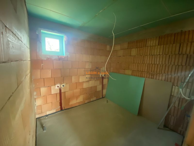 A construction room in a family house with brick walls and a small window.