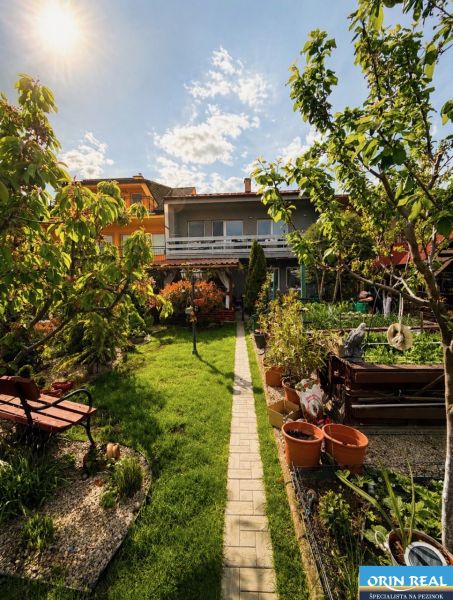 The garden of a family house on Muškátová Street in Pezinok with a bench and a walkway.
