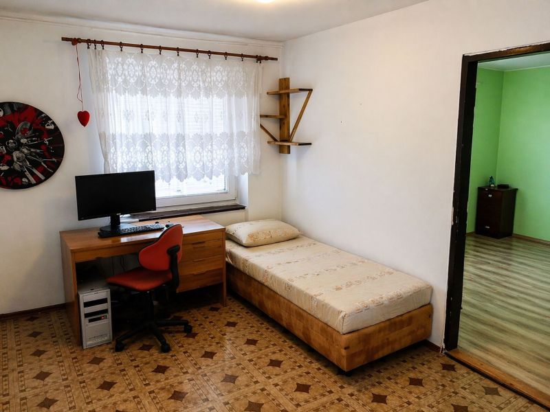A room with a computer and a bed, a floor with a wooden decor, a 3-room apartment.