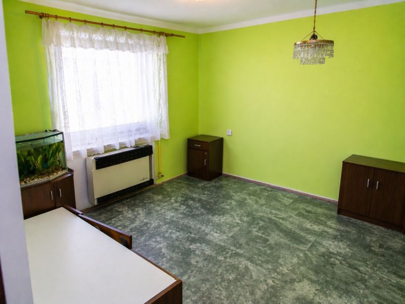 A green-painted room with an aquarium, curtains, and a chandelier in a 3-room apartment.