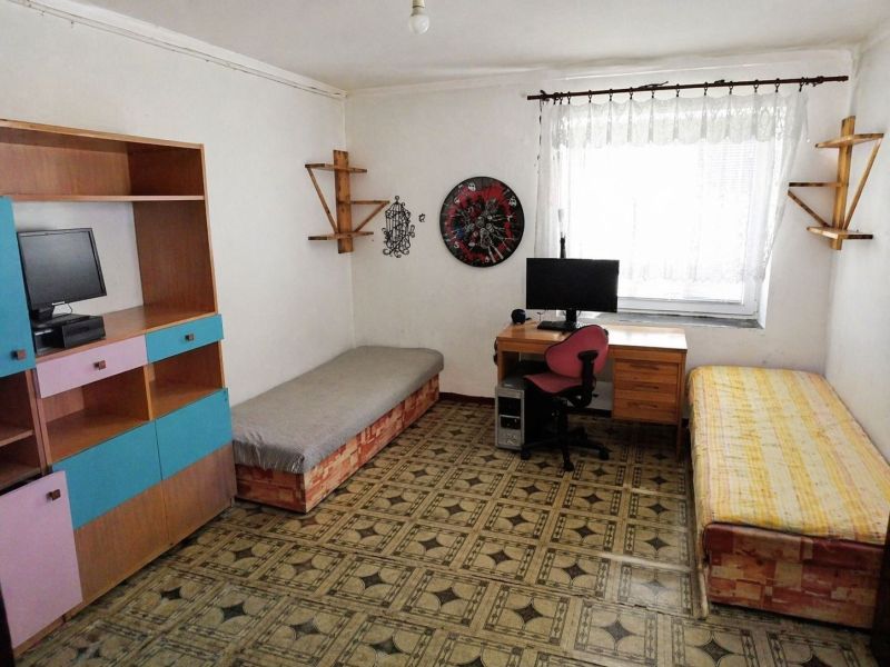 A room in a 3-bedroom apartment with a desk and beds.