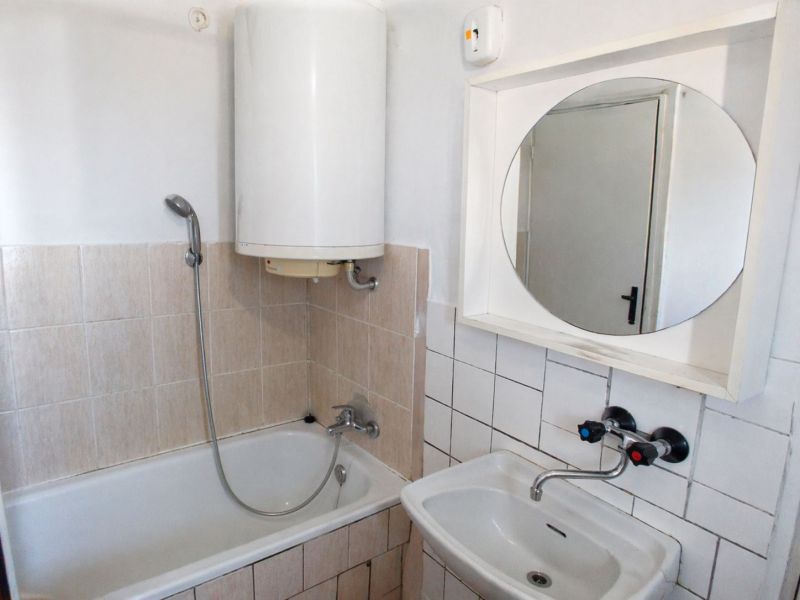 Bathroom with a bathtub, sink, and mirror in a 3-room apartment.