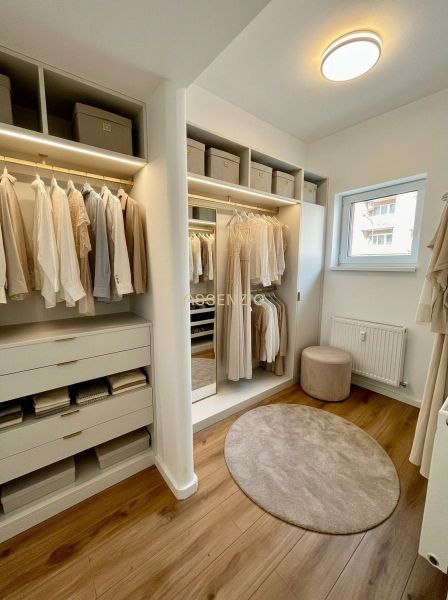 A wardrobe in a 4-room apartment with a wooden decor floor and light furniture.