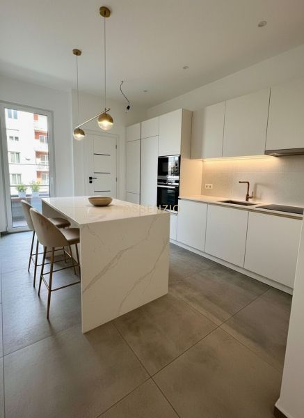 A kitchen with an island, light furniture, and pendant lights, in a 4-room apartment.