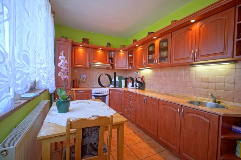 A kitchen with wooden decor, flowers on the table, and green walls in a family house.