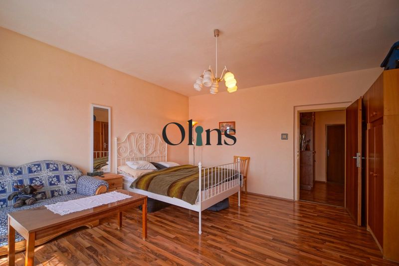 A bedroom in a family house with a bed, a sofa, and a wooden decor floor.
