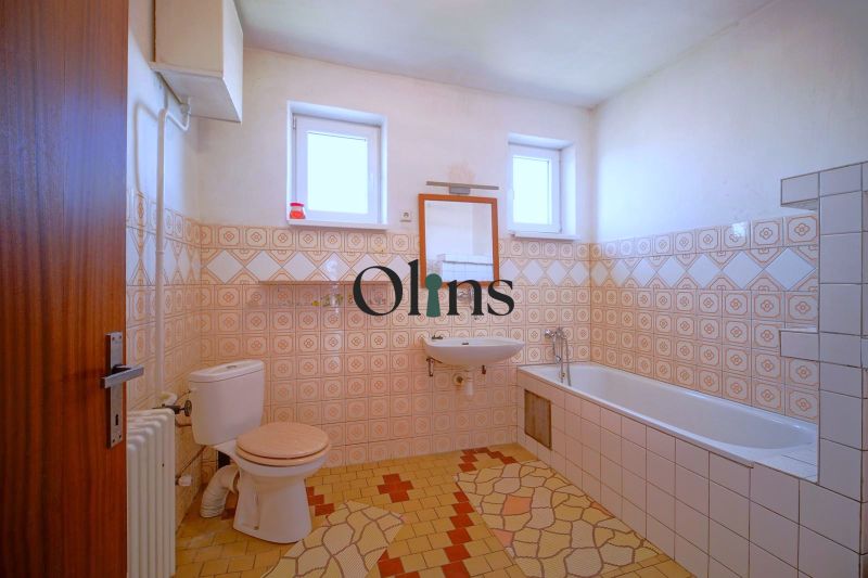 A bathroom in a family house with patterned tiles and a bathtub.
