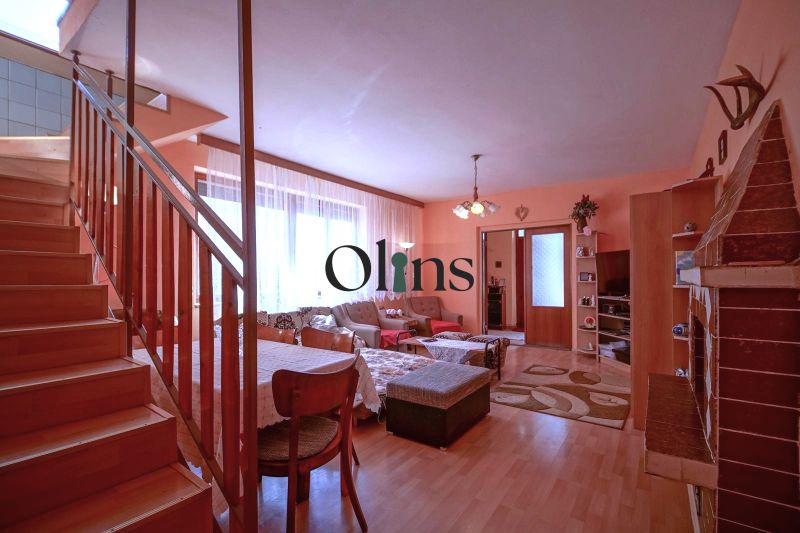 Interior of a family house with a fireplace, wooden decor flooring, and a staircase.