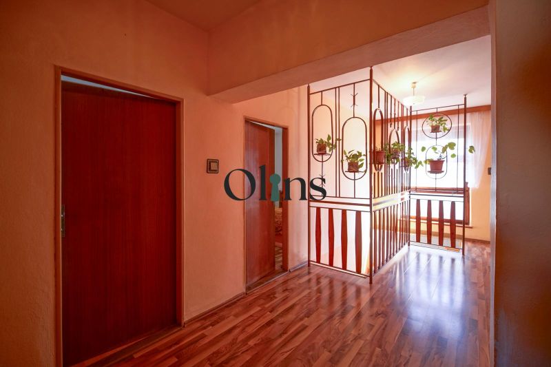 Hallway in a family house with a wooden decor floor and hanging flowers.