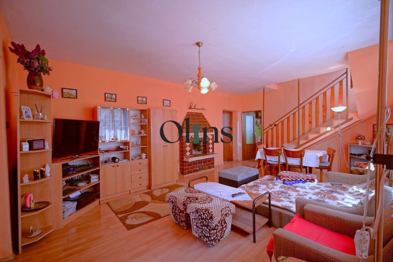 Living room in a family house with a staircase, fireplace, and wooden decor flooring.
