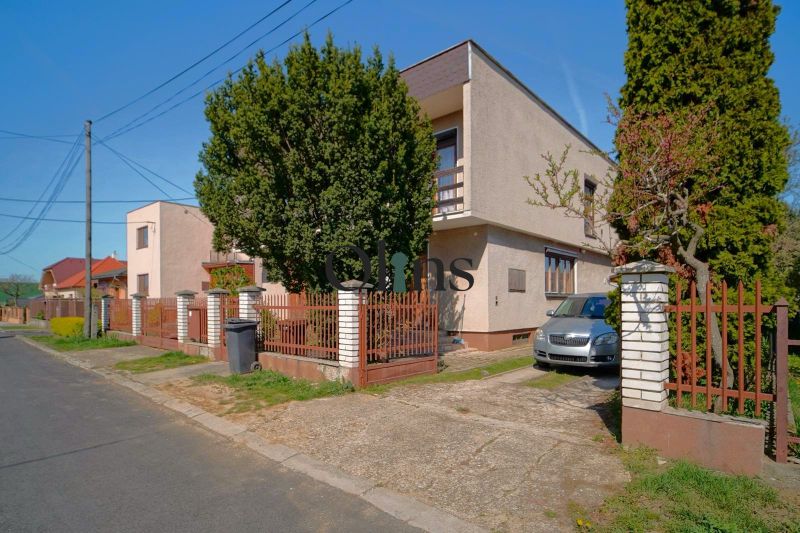 A family house in Veľký Lapáš with a front garden, a car, and a modified fence.