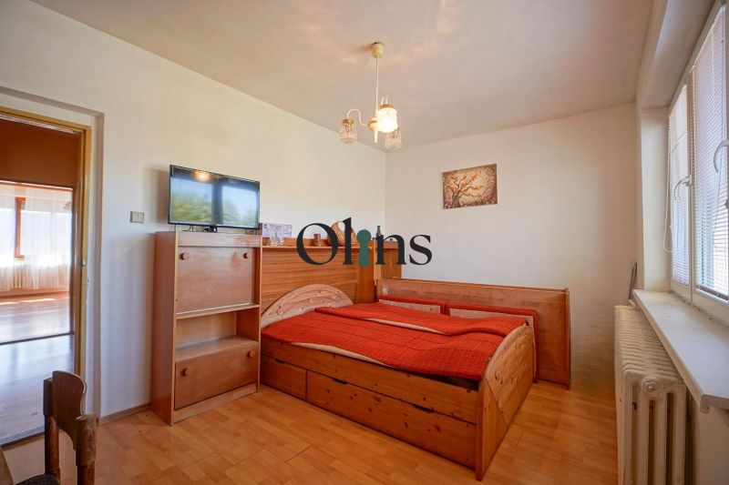 Bedroom with a bed, television, and wooden decor flooring in a family house.