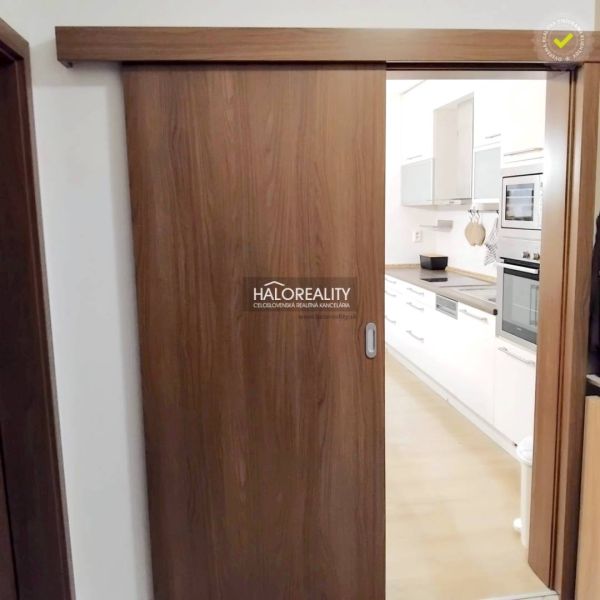 A kitchen with built-in appliances in a 2-room apartment, separated by wooden sliding doors.