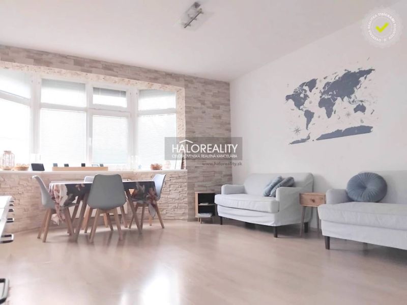 A bright living room in a two-room apartment with a wooden decor floor and a world map on the wall.