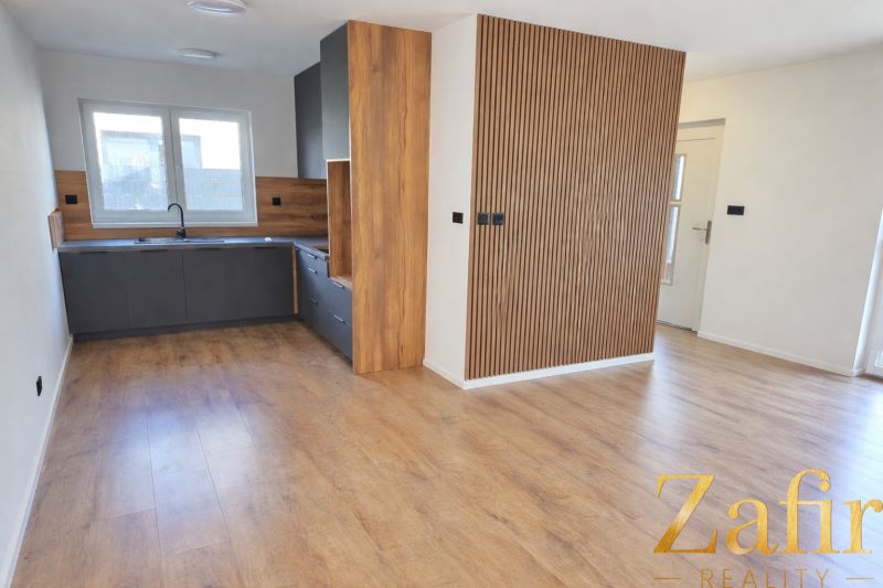 A kitchen in a family house with a wooden decor floor and wooden paneling.