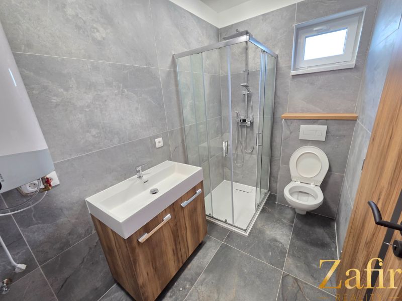 A bathroom in a family house with a modern shower and wooden decor cabinets.