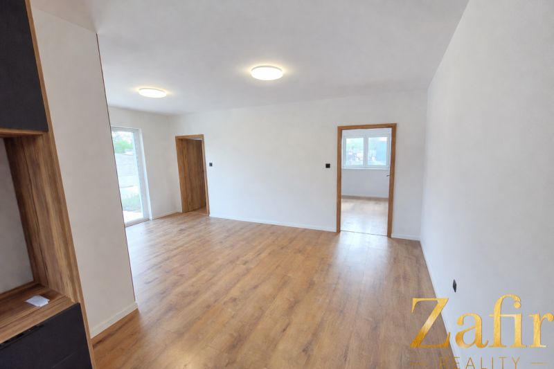 A room in a family house with white walls and a wooden decor floor.