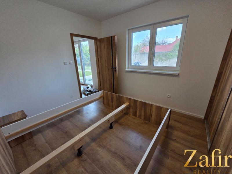 A room in a family house with a bed frame and a wooden decor floor.