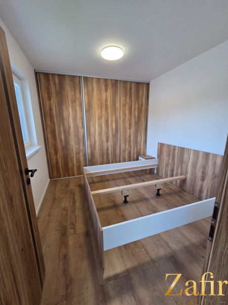 Bedroom in a family house with a bed and a wardrobe, floor with wooden decor.