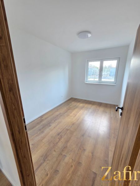 A room in a family house with a floor featuring a wooden decor and a window.
