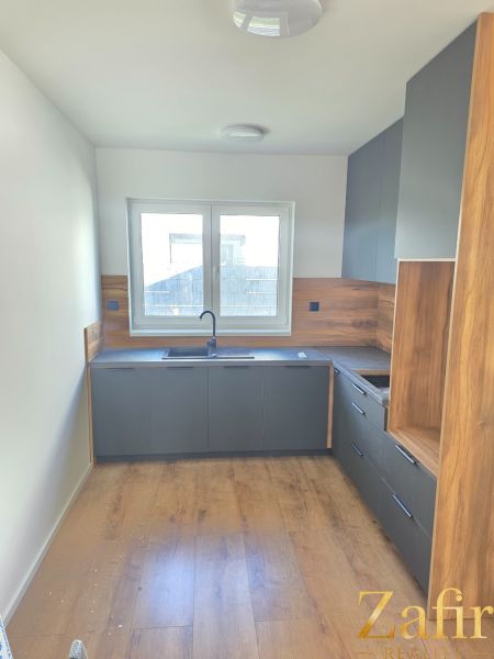 A kitchen in a family house with dark cabinets and a wood-patterned floor.