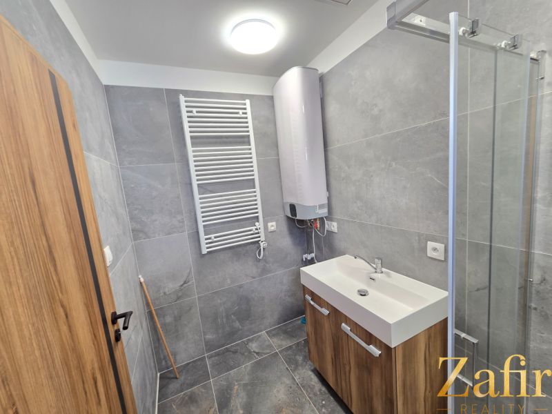 A bathroom with modern equipment and gray tiles in a family house.