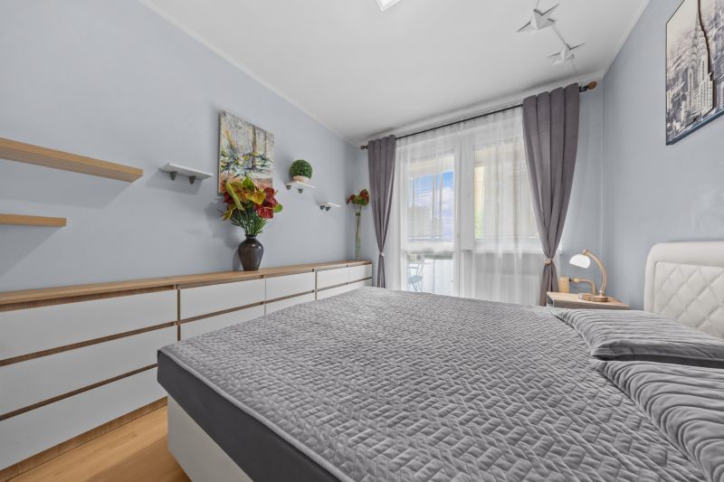 Bright bedroom in a 3-room apartment, gray bedspread, decorations, and floor with wood decor.
