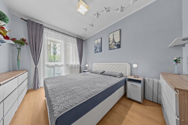 Bedroom with a bed, wooden decor flooring, and decorations in a 3-room apartment.