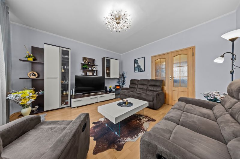 Living room in a three-room apartment with a wooden decor floor and a comfortable sofa set.