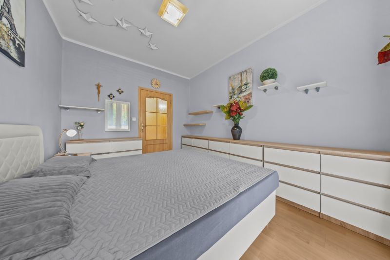 Bedroom in a 3-room apartment with a bed, furniture, and decorations, floor with wooden decor.